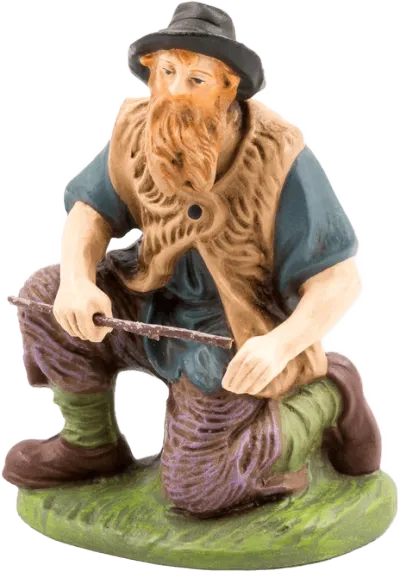 Kneeling shepherd figure holding firewood, hand-painted papier-mâché with blue shirt, brown vest, and green base