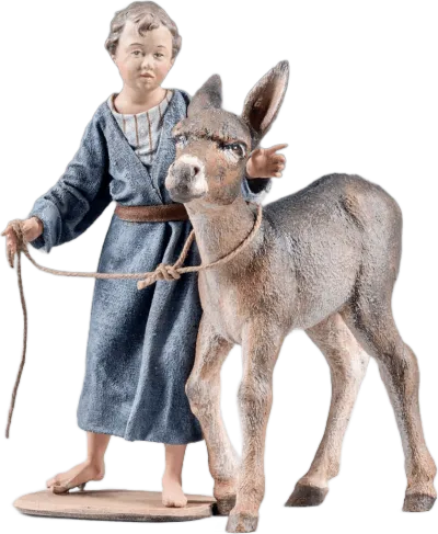 Hand-carved wooden boy figure in blue robe holding rope leading donkey foal with detailed paint and fabric clothing