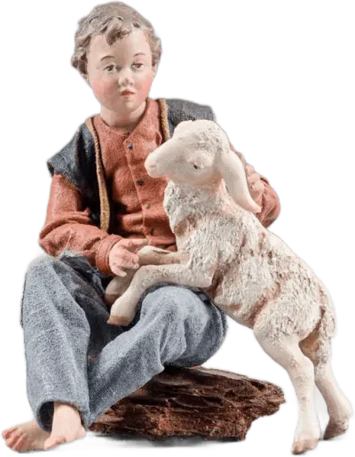 Hand-carved wooden figure of a boy sitting with a lamb, dressed in fabric clothing, painted in natural colors