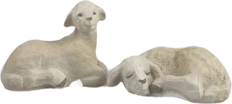 Two hand-carved and hand-painted wooden lamb figures, one lying down sleeping and one sitting upright, in muted white and beige tones